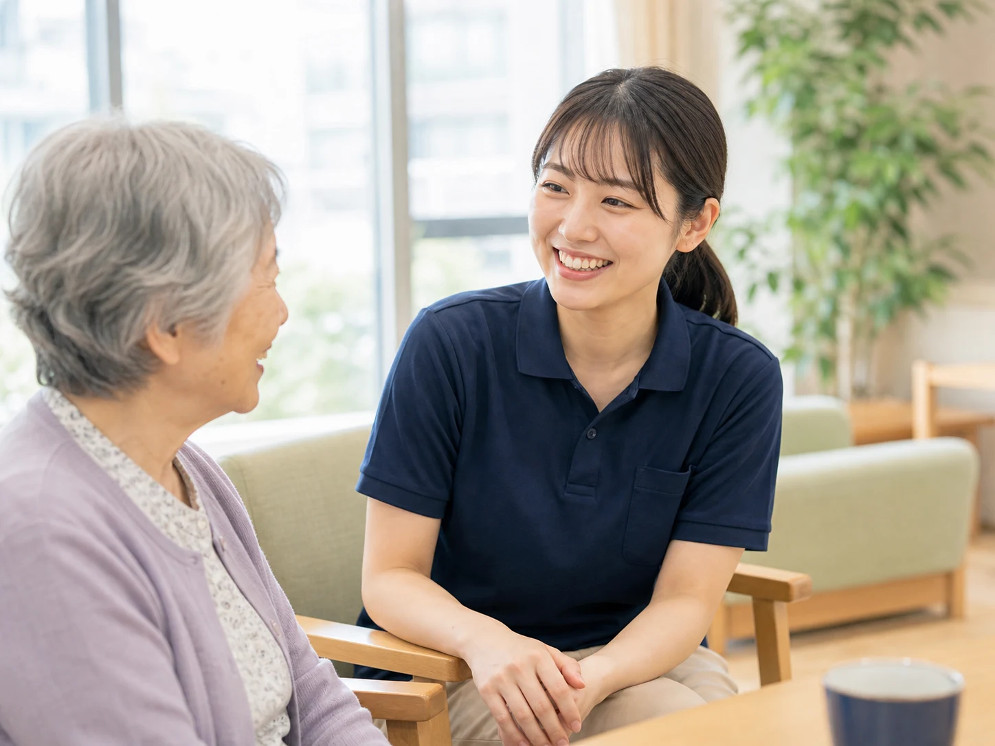 介護施設で笑顔で談笑する高齢女性と女性介護スタッフ